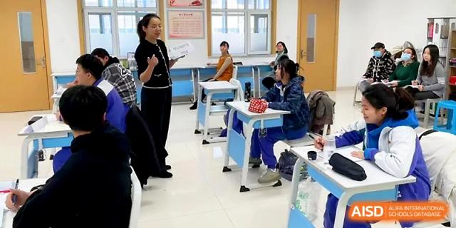 An instructor stands at the front of a bright classroom, guiding students through an interactive learning session at Yinchuan No.1 High School.