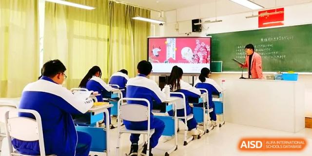Rows of students in blue uniforms sit at their desks, focusing on a multimedia presentation on the classroom screen at Yinchuan No.1 High School.