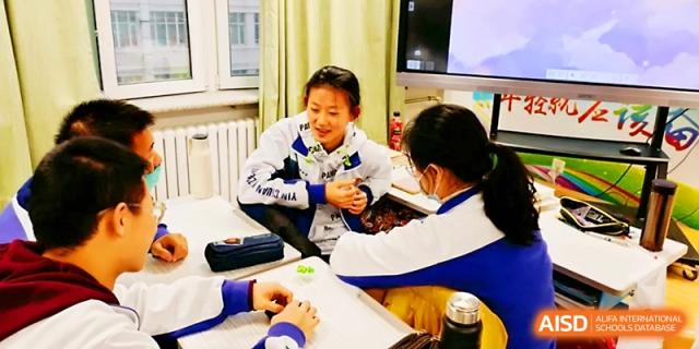 Two female students in school tracksuits sit together, engaged in a friendly and focused discussion at Yinchuan No.1 High School.