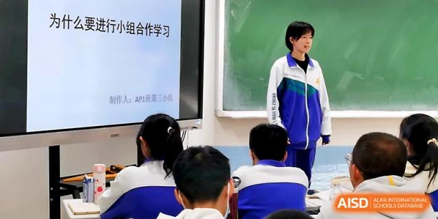 A female student stands next to a presentation screen to share her group's findings during a classroom project at Yinchuan No.1 High School.