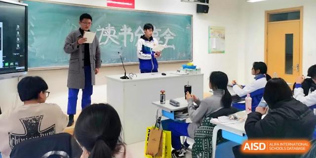 A student at a podium reads from a script during a formal classroom presentation or debate at Yinchuan No.1 High School.