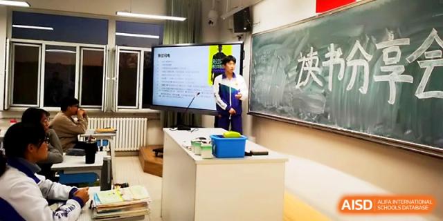A student stands next to a digital screen and podium, presenting an academic project to the rest of the class at Yinchuan No.1 High School.