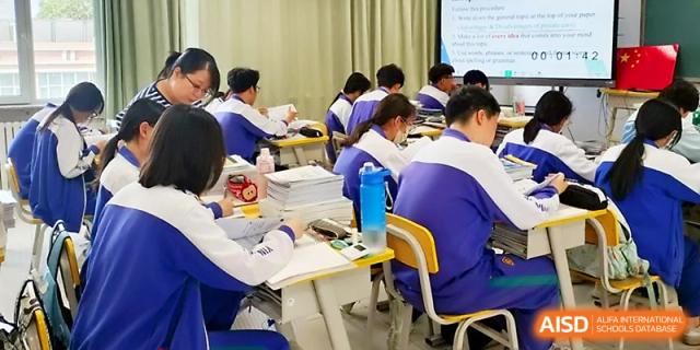 Students sit at long tables in a well-lit classroom, focusing on their textbooks and taking notes at Yinchuan No.1 High School.