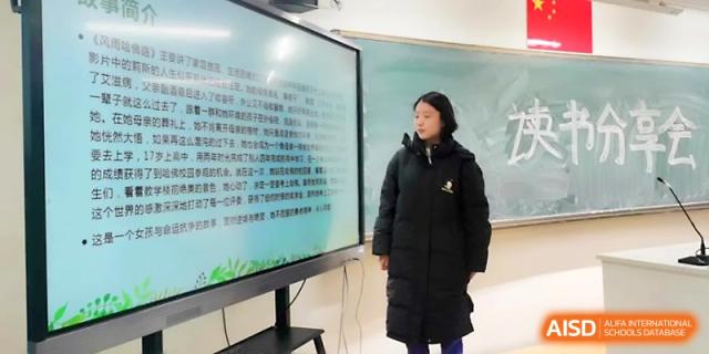 A student in a dark coat stands before a large digital monitor, leading an educational discussion in class at Yinchuan No.1 High School.