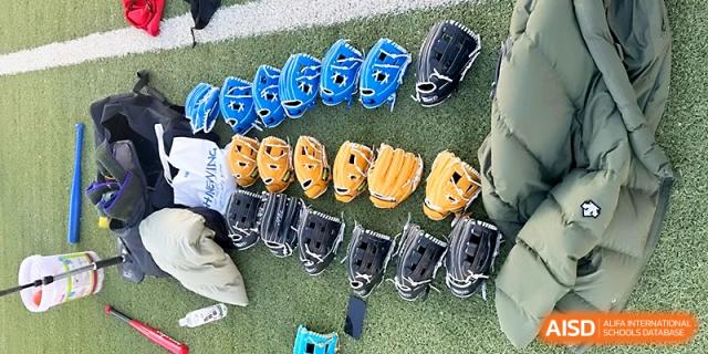Multiple rows of colorful baseball gloves in blue, yellow, and black are neatly arranged on the grass for student use at Yinchuan No.1 High School.