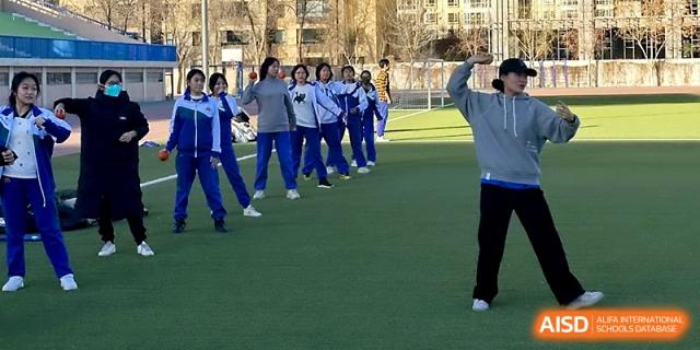 Students in blue and white tracksuits stand in formation on the green field, participating in a synchronized exercise at Yinchuan No.1 High School.