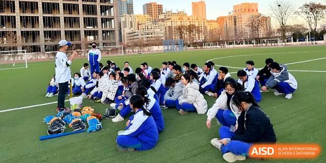 A large group of students in blue uniforms sits together on the grass, listening to instructions during a sports meet at Yinchuan No.1 High School.