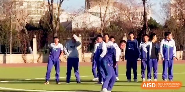 A group of boys in blue tracksuits prepares for a sports activity on the school's outdoor athletic grounds at Yinchuan No.1 High School.