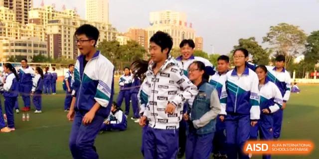 Students gather in small groups on the field, talking and preparing for their next physical education activity at Yinchuan No.1 High School.