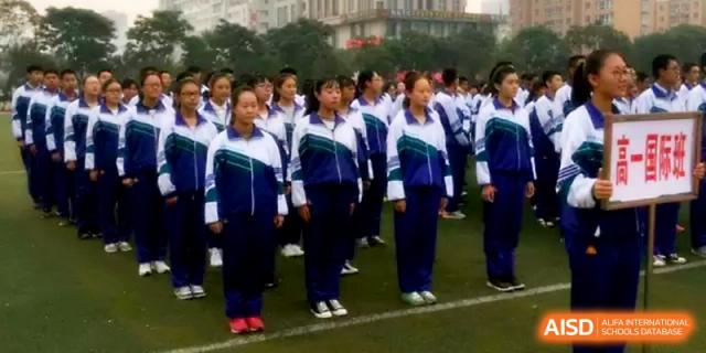 Rows of students in blue and white uniforms stand at attention during an outdoor assembly on the school's sports field at Yinchuan No.1 High School.