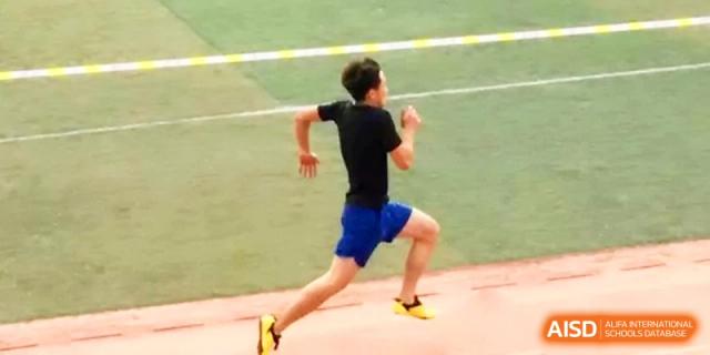 A male student in a black shirt sprints with speed and determination along the red running track during a race at Yinchuan No.1 High School.