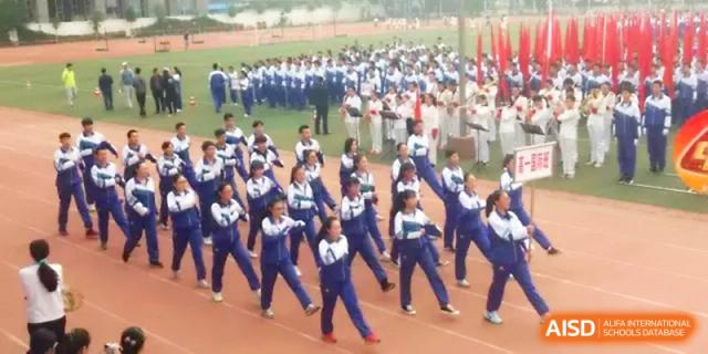 A large group of students performs a synchronized dance or exercise routine in rows on the outdoor field at Yinchuan No.1 High School.