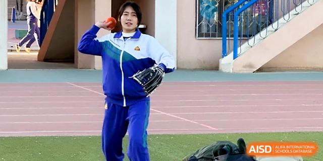 A female student wearing a blue tracksuit prepares to throw a ball during a field event at the outdoor sports meet for Yinchuan No.1 High School.
