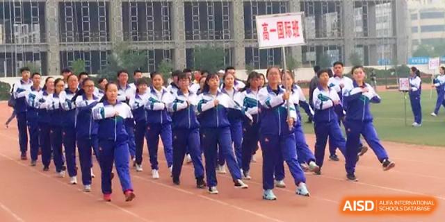 A group of female students in uniforms walks together along the red running track during a school sports festival at Yinchuan No.1 High School.