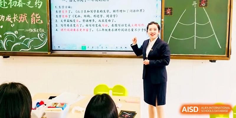 A teacher in a professional suit stands confidently in front of a digital whiteboard during a lesson at Zhangjiagang IVY Experimental School.