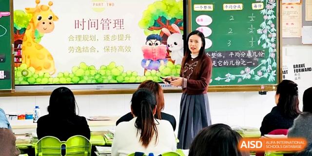 A teacher presents a lesson on time management using a colorful, illustrated background on a screen at Zhangjiagang IVY Experimental School.