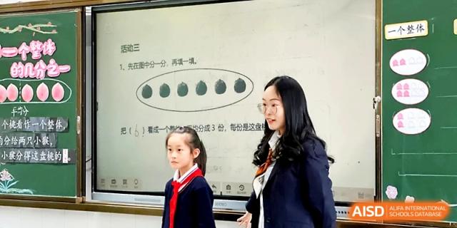 A teacher and a young student stand together in front of a whiteboard during a classroom lesson at Zhangjiagang IVY Experimental School.
