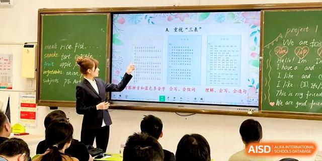 An educator uses a pointer to explain text on a large digital display for an audience at Zhangjiagang IVY Experimental School.