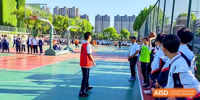 Students in red jerseys gather on an outdoor basketball court for a sports activity at Zhangjiagang IVY Experimental School.