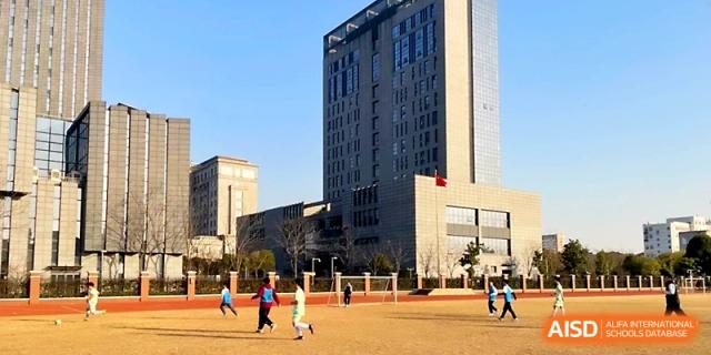 A wide shot shows the tall, modern architecture of the campus buildings under a clear blue sky at Zhangjiagang IVY Experimental School.