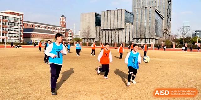 A group of boys in orange and blue jerseys participate in an outdoor physical education drill at Zhangjiagang IVY Experimental School.