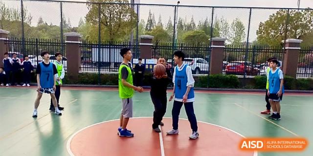 Students engage in a basketball practice session on an outdoor court with a coach at Zhangjiagang IVY Experimental School.