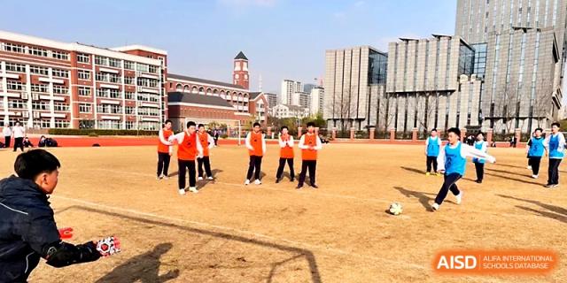 A line of students in orange vests prepares for a race on the school's outdoor sports field at Zhangjiagang IVY Experimental School.