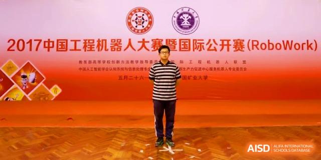 A student stands in front of a large red backdrop for a robotics competition ceremony at Zhangjiagang IVY Experimental School.