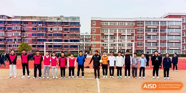 A long line of students and staff stands together for a group portrait on the athletic field at Zhangjiagang IVY Experimental School.
