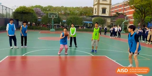 Young students practice basketball skills on a bright green and red outdoor court at Zhangjiagang IVY Experimental School.