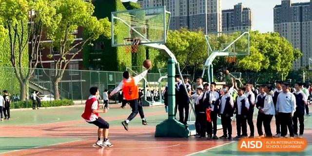 A student jumps high to make a basket during a competitive outdoor game at Zhangjiagang IVY Experimental School.