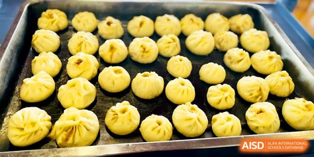 A tray filled with many rows of freshly prepared dumplings sits ready for steaming at Zhangjiagang IVY Experimental School.