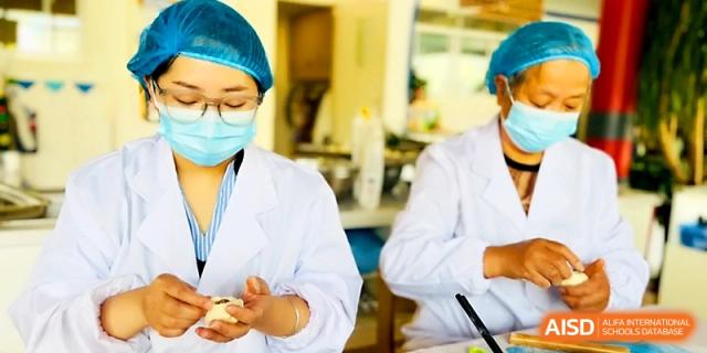 Kitchen staff in masks and hairnets work diligently to prepare large quantities of food at Zhangjiagang IVY Experimental School.