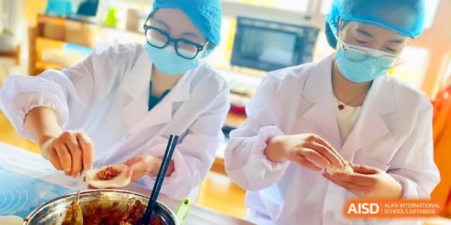 Food service workers focus on mixing ingredients in large metal bowls for the day's menu at Zhangjiagang IVY Experimental School.
