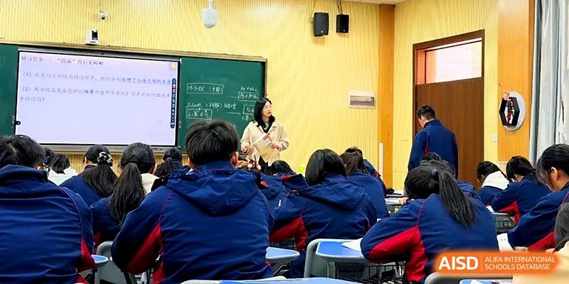 A female instructor leads a dynamic classroom discussion with students in blue and red uniforms at Zhejiang ZhouShan High School.