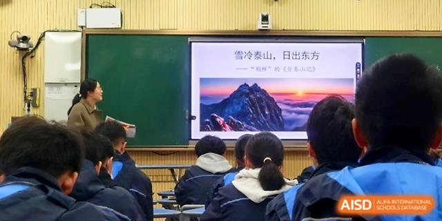 Students watch a presentation featuring a scenic mountain sunrise on a large digital screen in class at Zhejiang ZhouShan High School.