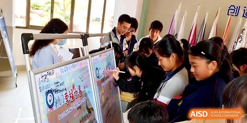 Students gather around a large poster board to collaborate on a creative project during a school event at Zhejiang ZhouShan High School.