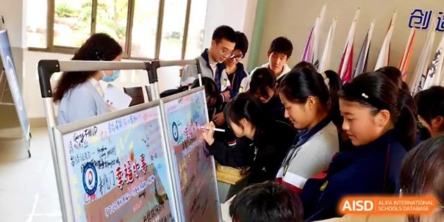 Students gather around a large poster board to collaborate on a creative project during a school event at Zhejiang ZhouShan High School.