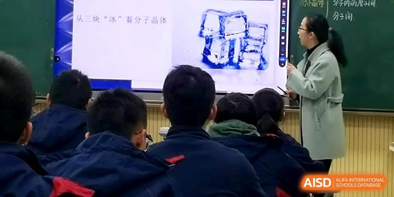 Students look closely at a digital whiteboard displaying complex blue diagrams during a science lesson at Zhejiang ZhouShan High School.