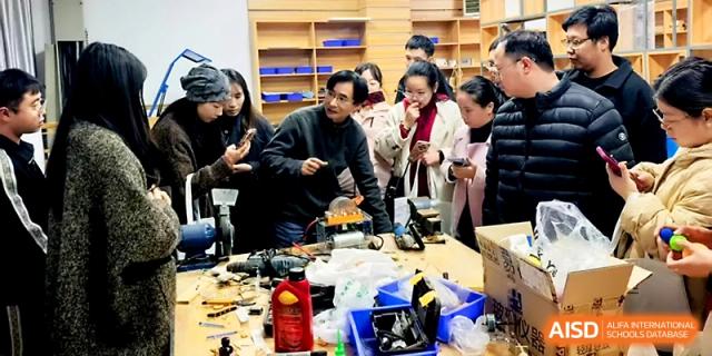 A group of people gathers around a table for a hands-on technical demonstration involving electronic parts at Zhejiang ZhouShan High School.