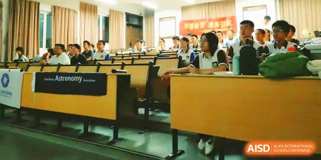 Students sit at long desks in a bright, modern classroom during a collaborative group learning activity at Zhejiang ZhouShan High School.