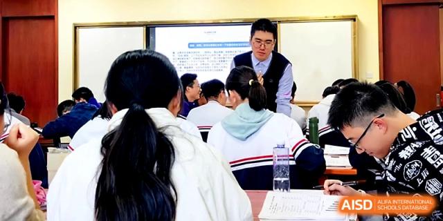 A male teacher interacts closely with students at their desks to provide personalized academic guidance at Zhejiang ZhouShan High School.