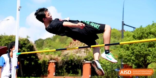 A male athlete performs a high jump using the Fosbury Flop technique over a bar during an outdoor competition at Zhejiang ZhouShan High School.