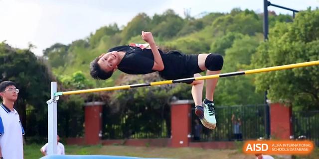 A student successfully clears the high jump bar with great form during an intense track and field event at Zhejiang ZhouShan High School.