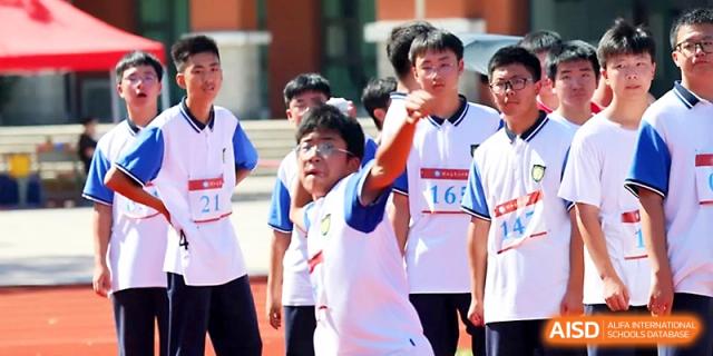 A student prepares to launch a shot put during a field event as others watch the competition at Zhejiang ZhouShan High School.