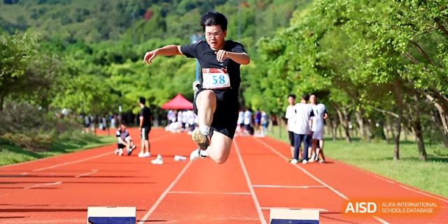 An athlete in mid-air performs a long jump into the sand pit during a track and field competition at Zhejiang ZhouShan High School.