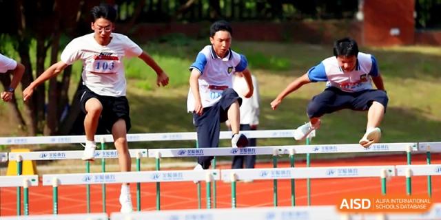 A male student jumps with agility over a hurdle during a track and field hurdling event at Zhejiang ZhouShan High School.