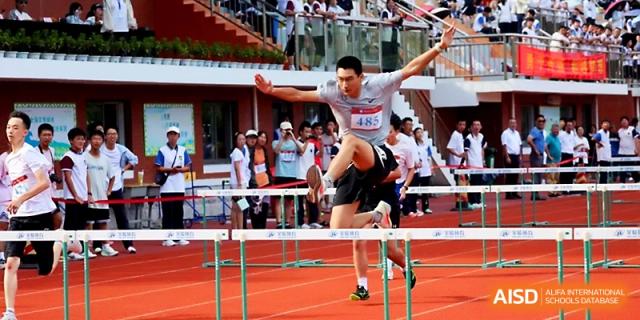 A student displays impressive form and balance while jumping over a hurdle on the red track at Zhejiang ZhouShan High School.