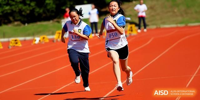 Two female students sprint side-by-side in a competitive race on the athletic track at Zhejiang ZhouShan High School.