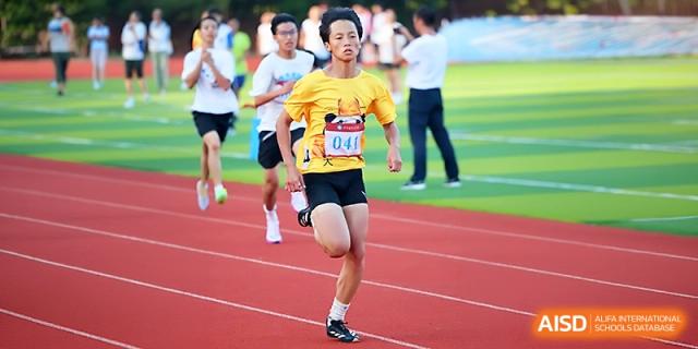 A student in a yellow shirt leads a group of runners during a track competition on a clear day at Zhejiang ZhouShan High School.